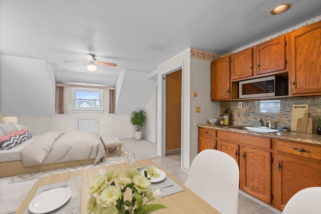 kitchen with tasteful backsplash, sink, light tile patterned floors, and ceiling fan