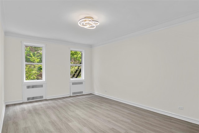 spare room featuring radiator, ornamental molding, and light hardwood / wood-style floors