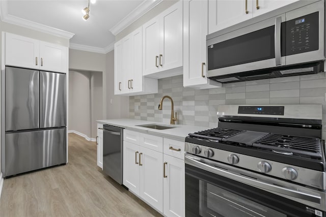 kitchen with sink, crown molding, stainless steel appliances, light hardwood / wood-style floors, and white cabinets