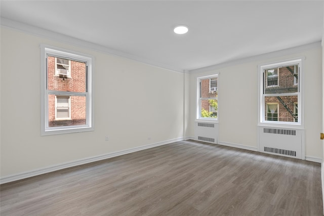 spare room featuring hardwood / wood-style flooring, crown molding, and radiator