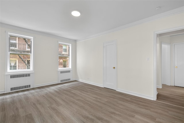 unfurnished room featuring crown molding, radiator, and hardwood / wood-style floors