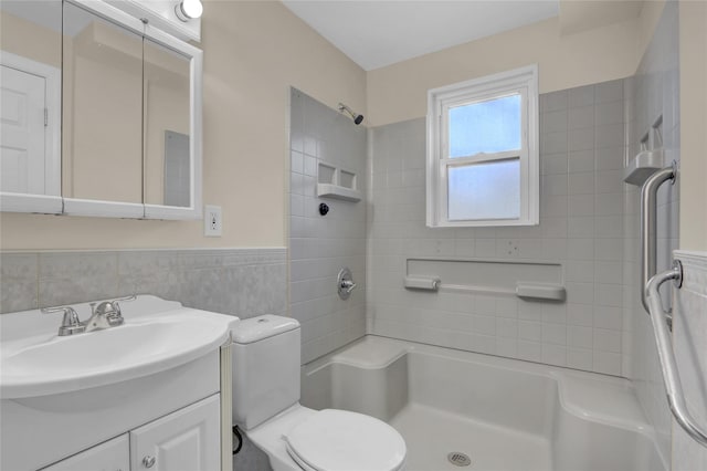 bathroom with vanity, toilet, tile walls, and a tile shower