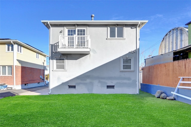 back of property with a balcony and a lawn