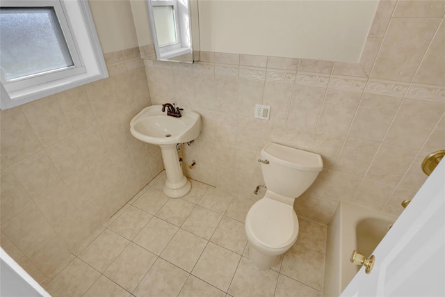 bathroom with tile patterned flooring, a tub to relax in, tile walls, and toilet