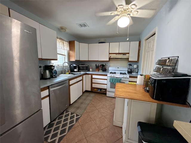 kitchen with sink, white cabinets, light tile patterned floors, ceiling fan, and stainless steel appliances