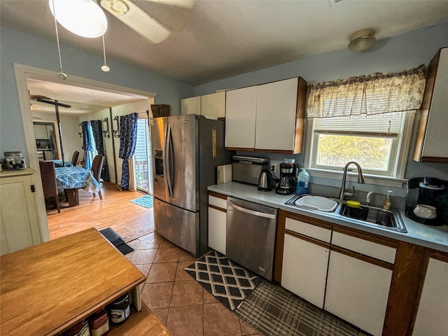 kitchen featuring white cabinetry, sink, light tile patterned floors, ceiling fan, and stainless steel appliances