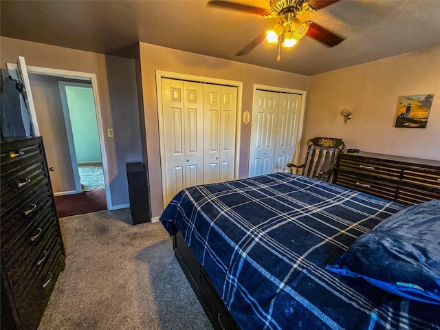 bedroom with ceiling fan, two closets, and dark colored carpet