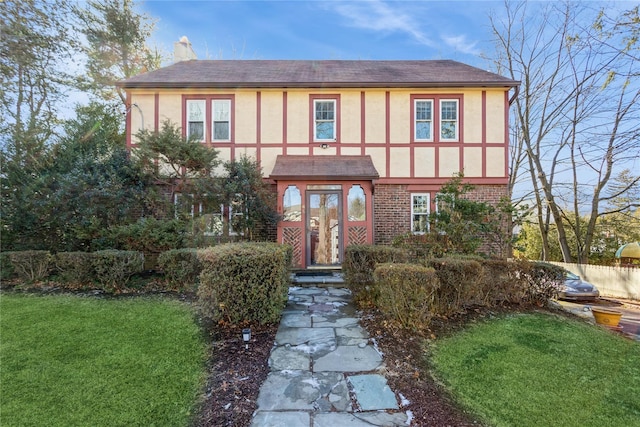 tudor house with a front yard and french doors