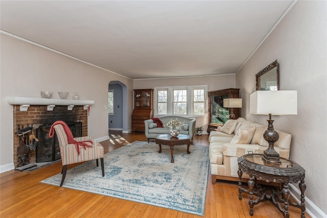 living room featuring ornamental molding, wood-type flooring, and a fireplace