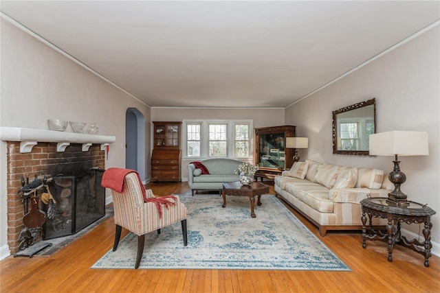 living room featuring crown molding, a brick fireplace, and light hardwood / wood-style floors