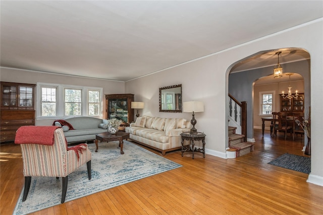 living room with a notable chandelier, crown molding, and wood-type flooring