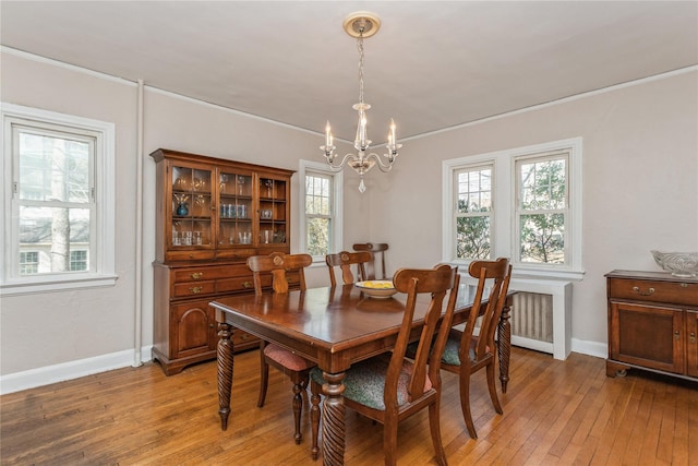 dining space featuring crown molding, radiator heating unit, a chandelier, and light wood-type flooring