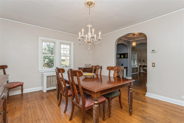 dining area featuring crown molding, radiator, a notable chandelier, and light hardwood / wood-style floors