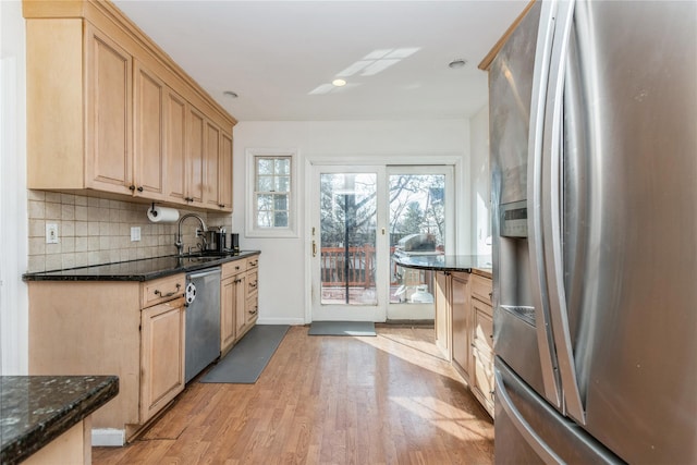 kitchen with sink, stainless steel appliances, dark stone counters, and light brown cabinets