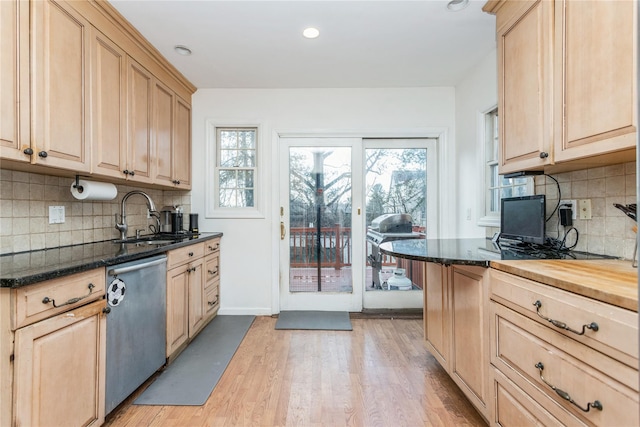 kitchen with sink, light brown cabinets, light wood-type flooring, dishwasher, and dark stone counters