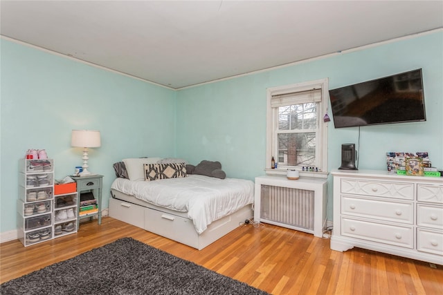 bedroom with radiator heating unit and light hardwood / wood-style flooring