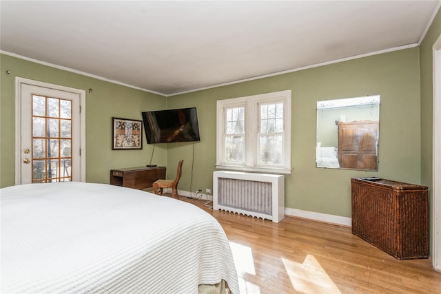 bedroom featuring multiple windows, crown molding, radiator heating unit, and light hardwood / wood-style flooring