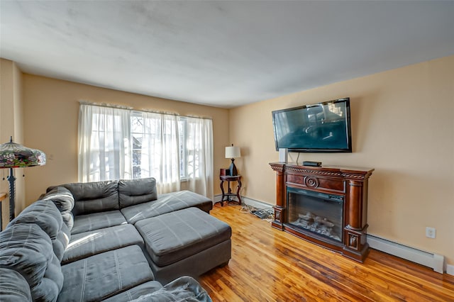 living room with a baseboard heating unit and light wood-type flooring