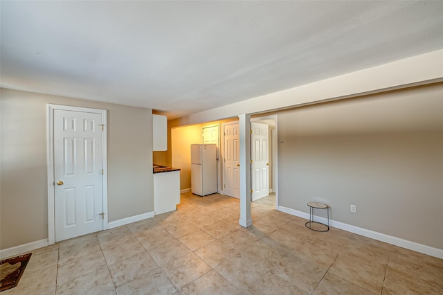 interior space featuring light tile patterned flooring, white fridge, and two closets