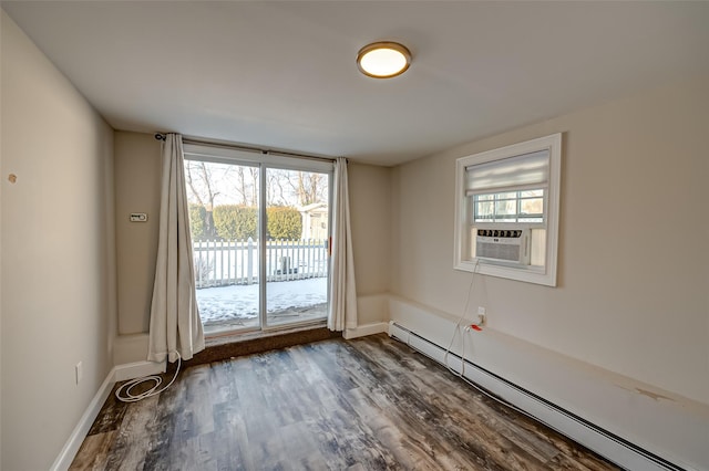 spare room featuring cooling unit, a baseboard heating unit, and dark wood-type flooring