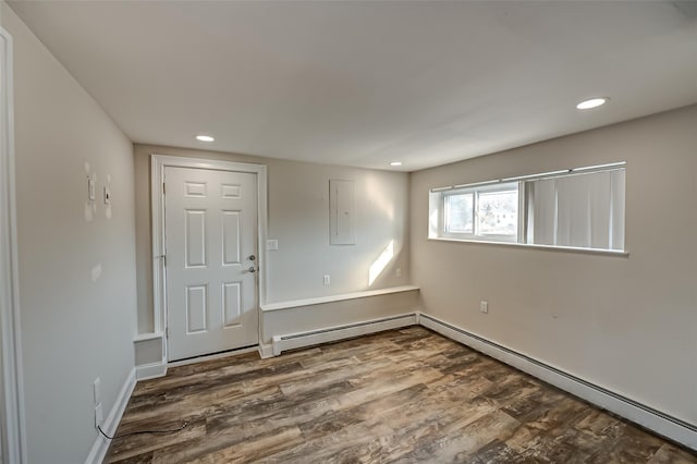 unfurnished room with baseboard heating, wood-type flooring, and electric panel