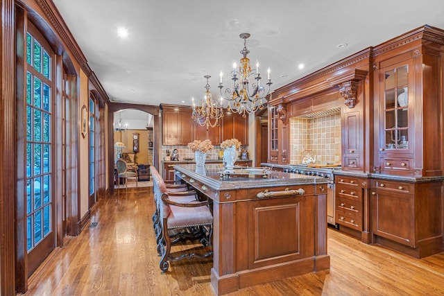 183 Mill Spring Rd, Manhasset, NY 11030 - kitchen featuring glass insert cabinets, a center island, a notable chandelier, high end stainless steel range oven, and arched walkways