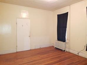 empty room featuring radiator and hardwood / wood-style floors