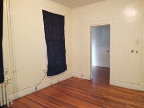 spare room with radiator heating unit and dark hardwood / wood-style flooring