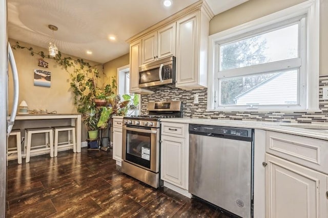 kitchen featuring tasteful backsplash, stainless steel appliances, decorative light fixtures, and dark hardwood / wood-style flooring