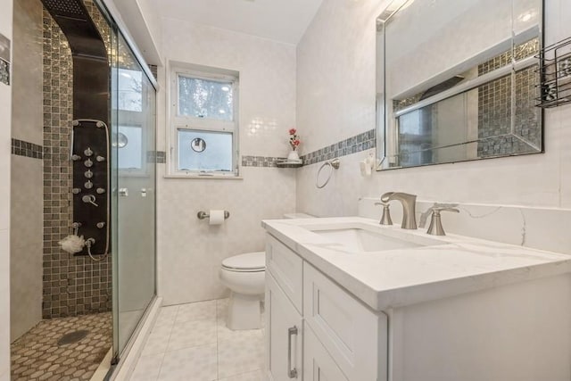 bathroom featuring tile patterned floors, toilet, tile walls, vanity, and a shower with door