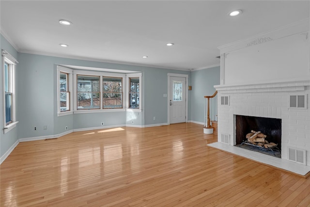 unfurnished living room with ornamental molding, a brick fireplace, and light wood-type flooring