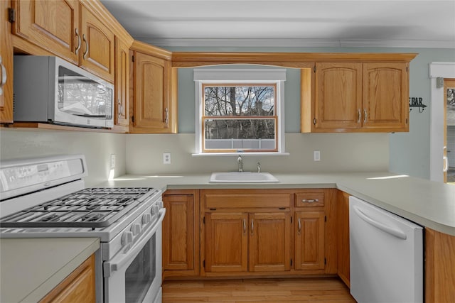 kitchen featuring ornamental molding, sink, white appliances, and light wood-type flooring