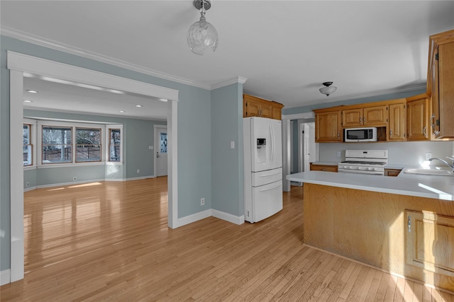 kitchen with sink, white appliances, light hardwood / wood-style flooring, hanging light fixtures, and kitchen peninsula