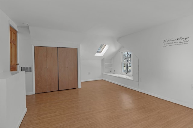 bonus room featuring lofted ceiling with skylight and light wood-type flooring