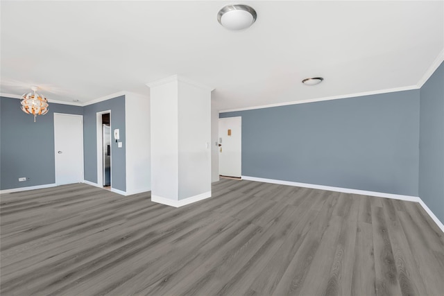 spare room with wood-type flooring, ornamental molding, and an inviting chandelier