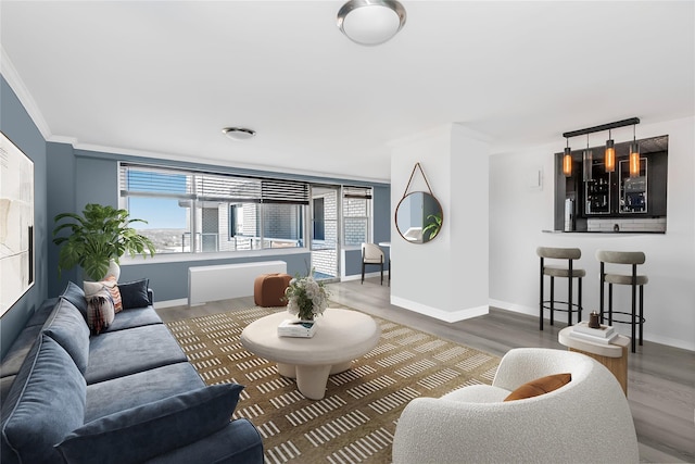 living room featuring ornamental molding, wood-type flooring, and bar area