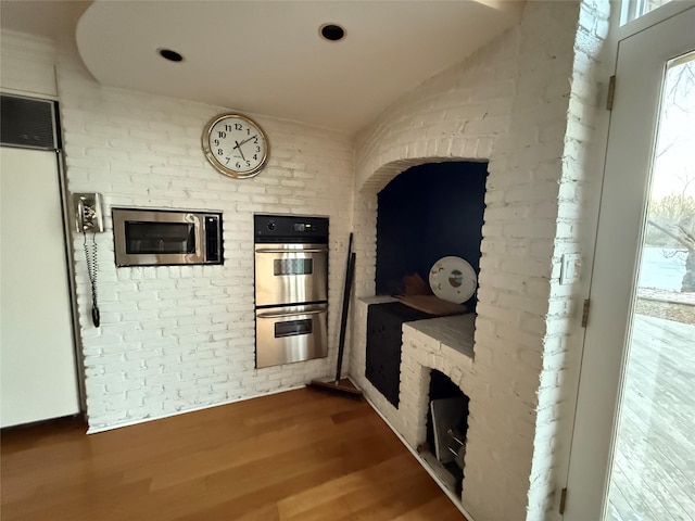 interior space with brick wall and hardwood / wood-style floors