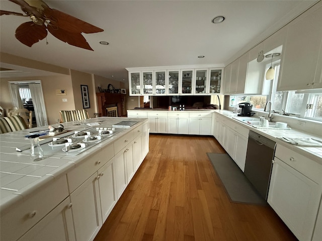 kitchen featuring sink, white cabinets, tile counters, stainless steel dishwasher, and light hardwood / wood-style floors