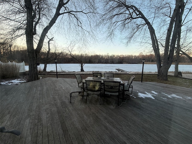 deck at dusk featuring a water view