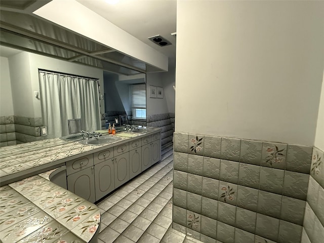 kitchen featuring gray cabinetry, sink, and tile walls