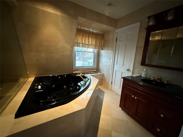 bathroom featuring a relaxing tiled tub, vanity, and tile patterned flooring