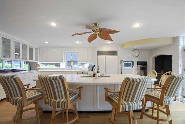 1 Lake Dr, Middle Island, NY 11953 - kitchen with built in appliances, tile countertops, white cabinets, wood finished floors, and a ceiling fan
