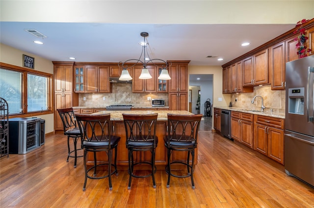 kitchen featuring light stone countertops, decorative light fixtures, stainless steel appliances, and a kitchen island