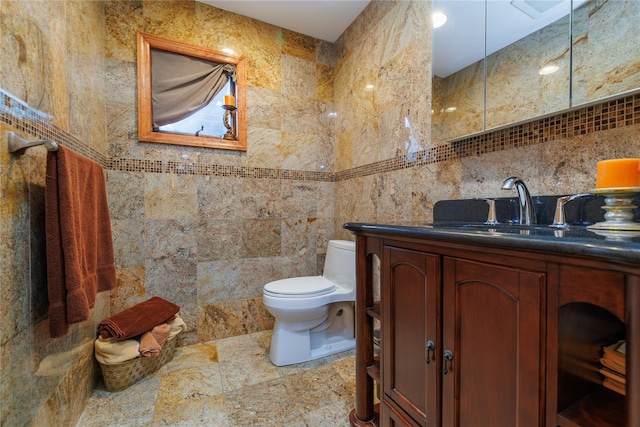 bathroom with vanity, toilet, and tile walls