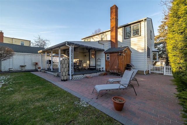 rear view of house with a storage shed, a patio area, and a lawn