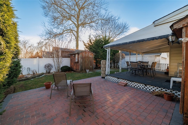 patio terrace at dusk featuring a storage shed and a wooden deck