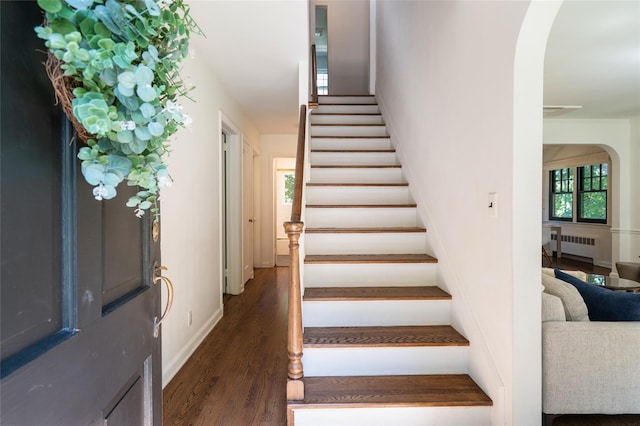 staircase featuring hardwood / wood-style flooring and radiator heating unit