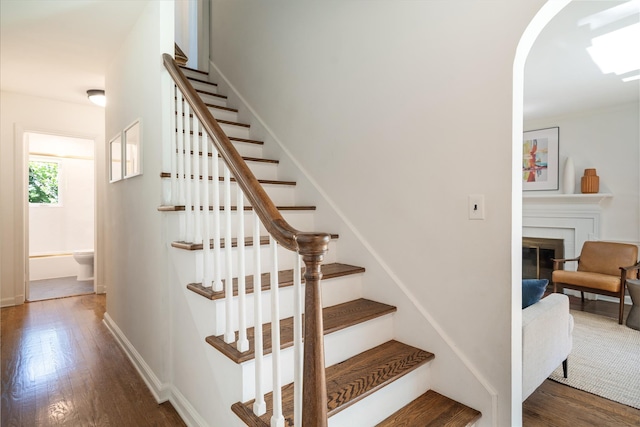 stairway featuring wood-type flooring and a brick fireplace