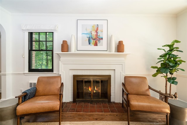 living area with crown molding and a brick fireplace