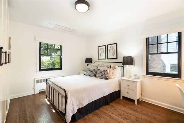 bedroom featuring dark wood-type flooring, radiator, and multiple windows